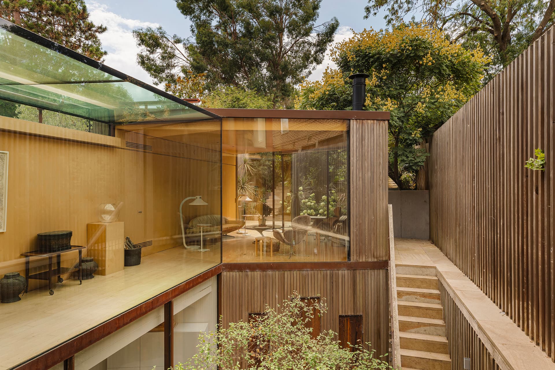 Timber and glass garden pavilion with a corten steel frame, seen from the terrace steps